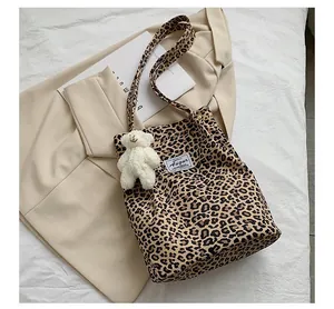 Détail d'un sac à bandoulière léopard avec un adorable charm en peluche d'ours blanc