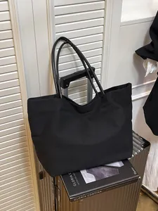 Large capacity black canvas tote bag for women, minimalist style on a silver suitcase.