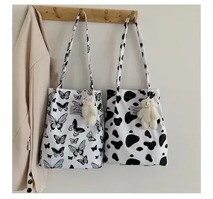 Détail de sacs fourre-tout à motifs papillon et vache avec porte-clés ours en peluche