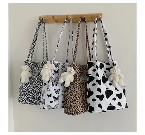 Vue détaillée de sacs fourre-tout à imprimé animal avec des charms d'ours en peluche.