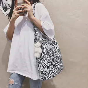 Stylish black and white zebra pattern tote bag with a cute plush bear charm on model