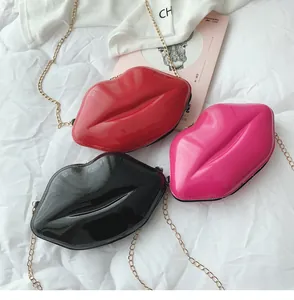Dettaglio della finitura lucida delle mini borse a labbro rosse, rosa e nere su fondo bianco.