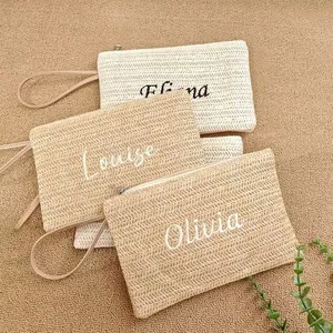 Detailed view of handwoven straw clutches with personalized name embroidery for travel.