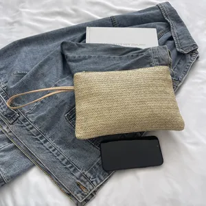 Detail view showing texture of handmade straw woven wristlet clutch on denim jacket