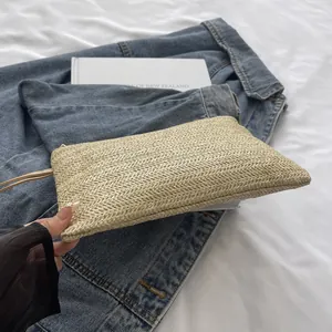 Close-up of minimalist straw woven clutch bag on a denim jacket backdrop