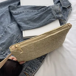 Detailed macro view of a minimalist woven straw clutch bag with premium gold zipper