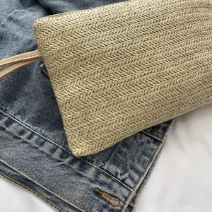 Close-up of the intricate diagonal weave pattern on a natural straw vacation clutch bag.