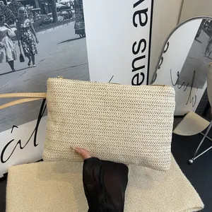 Close-up view of a minimalist beige woven straw clutch bag for beach vacations.