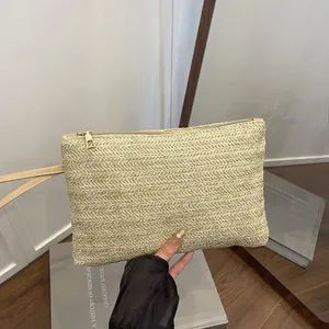 Detailed view of handmade woven straw clutch bag with gold zipper for beach vacation