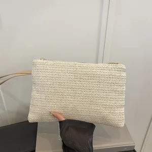 Detail view of a cream minimalist woven straw wristlet bag perfect for beach vacations.
