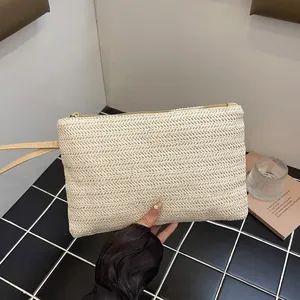 Detailed view of the cream woven straw clutch bag texture and minimalist wristlet