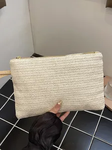 Handheld minimalist woven straw clutch bag for beach and summer vacations.