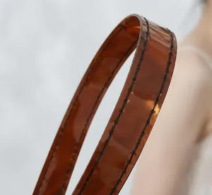 Detail view of brown transparent jelly bag strap with durable black stitching