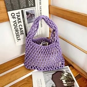 Close-up detail of purple hand-knitted cotton rope hollow mesh bucket bag on wooden shelf