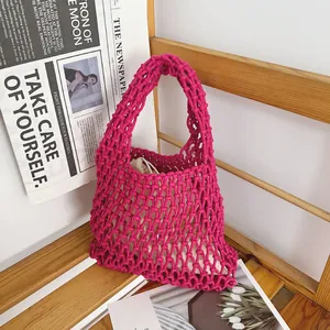 Close-up of magenta handmade woven cotton rope bag with hollow net design and inner pouch.