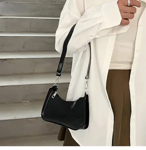 Detailed shot of a chic black glossy underarm shoulder bag worn with a white shirt.
