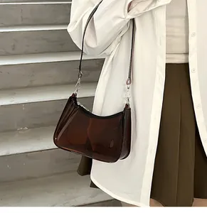 Stylish brown transparent jelly underarm bag with silver hardware worn by a model.