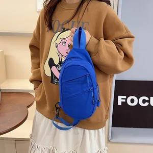 Modern blue nylon sling bag with adjustable strap shown on a casual brown sweatshirt