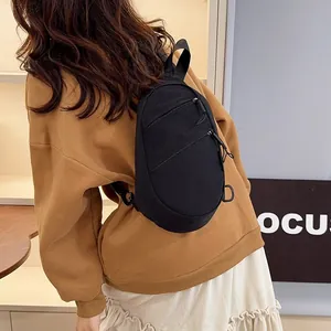 Detailed view of the black nylon sling bag worn as a crossbody chest pack.