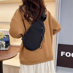 Close-up back view of a black nylon casual sling bag worn over a brown sweater outfit