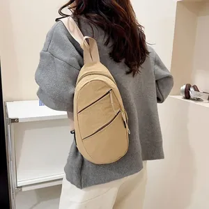 Detailed view of a beige nylon casual chest bag worn by a model in a minimal setting