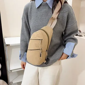 Detailed close-up of a beige nylon casual sling bag worn over a grey knitted sweater