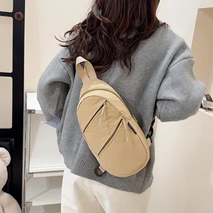 Detailed back view of a person wearing a beige nylon sling bag as a casual crossbody chest pack.