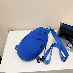 Vibrant blue nylon crossbody sling bag displayed on a clean white minimalist desk