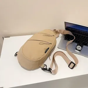 Close-up of khaki nylon sling bag showing dual zipper pockets and wide adjustable strap