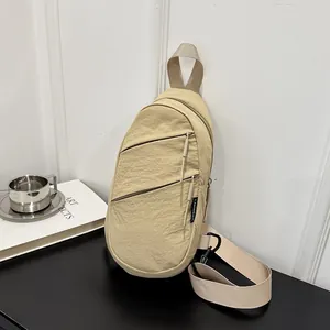 Detail view of the beige nylon chest bag with layered zippers and minimalist style.