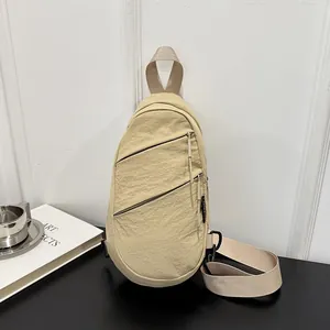 Close-up detail of a minimalist khaki nylon sling chest bag in a lifestyle setting