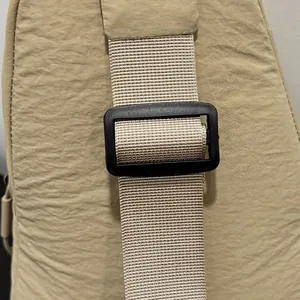 Close-up of beige nylon crossbody bag strap with adjustable black plastic buckle detail