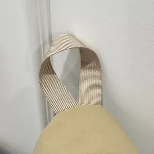 Close-up detail of the durable nylon webbing handle on a minimalist beige crossbody bag.