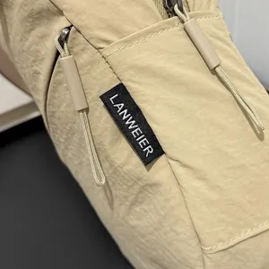 Close-up of beige nylon fabric texture and LANWEIER brand label on crossbody bag