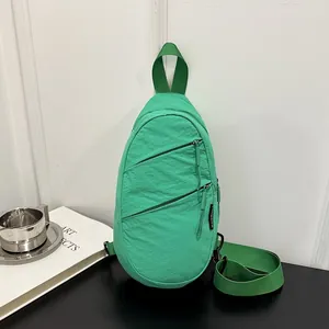 Close-up of green nylon sling bag with diagonal zippers for casual sports wear