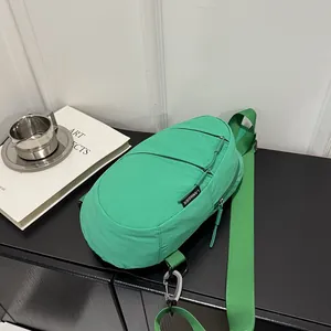 Detail of a bright green nylon chest bag featuring functional zippers and branding.