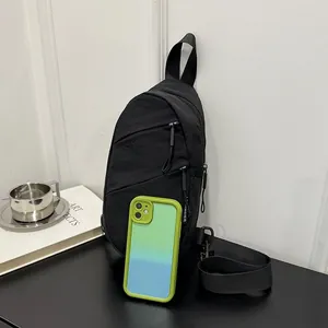 Close-up detail of a black nylon sling bag shown next to a smartphone for size reference