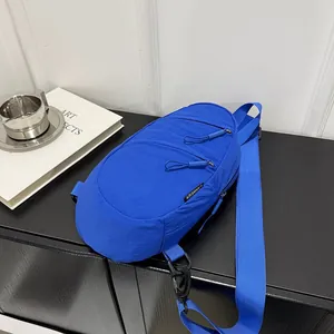 Macro view of bright blue nylon chest bag featuring functional zippers and brand tag.