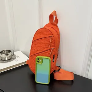 Vibrant orange nylon chest bag shown alongside a smartphone for scale comparison.