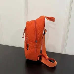 Close-up side view of an orange nylon chest bag with zipper and strap details