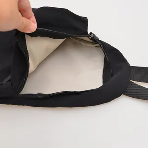 Detail view of the beige interior lining and smooth zipper of the black nylon bag.