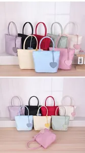 Multiple colorful nylon tote bags with heart pendants shown in a cozy lifestyle set