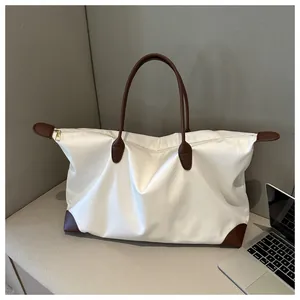 Close-up of a large white travel tote bag with brown leather handles in a commuter scene