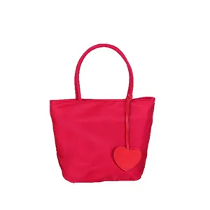 Vibrant red nylon tote bag for women featuring a cute heart-shaped charm pendant