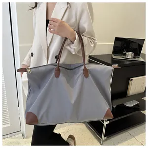 Amplio bolso tote de nailon gris con asas de cuero marrón llevado por una mujer