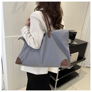 Stylish woman carrying a large grey nylon travel tote bag with durable brown leather accents