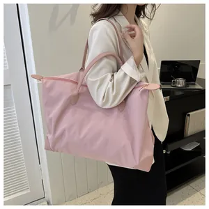 Woman carrying a large pink nylon travel tote bag for commuting in a modern indoor setting