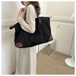 Large capacity black nylon travel tote bag with brown leather handles shown on model