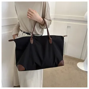 Spacious black nylon travel tote with durable brown leather handles and corner details