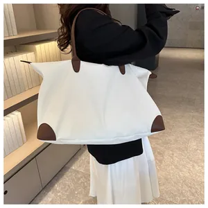 Detailed view of a woman carrying a large white travel tote with brown leather straps